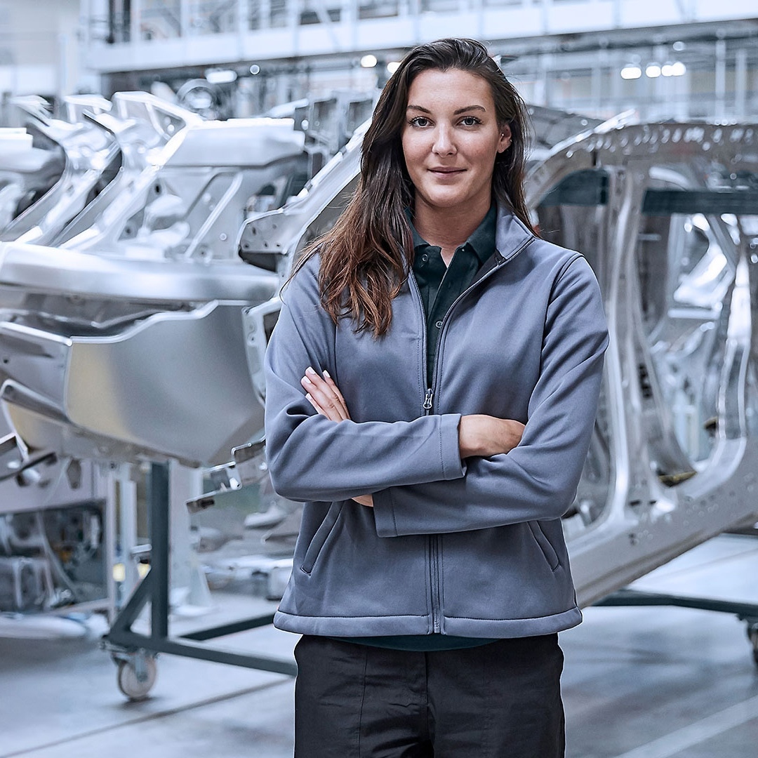 Woman stands with her arms crossed in front of vehicle parts