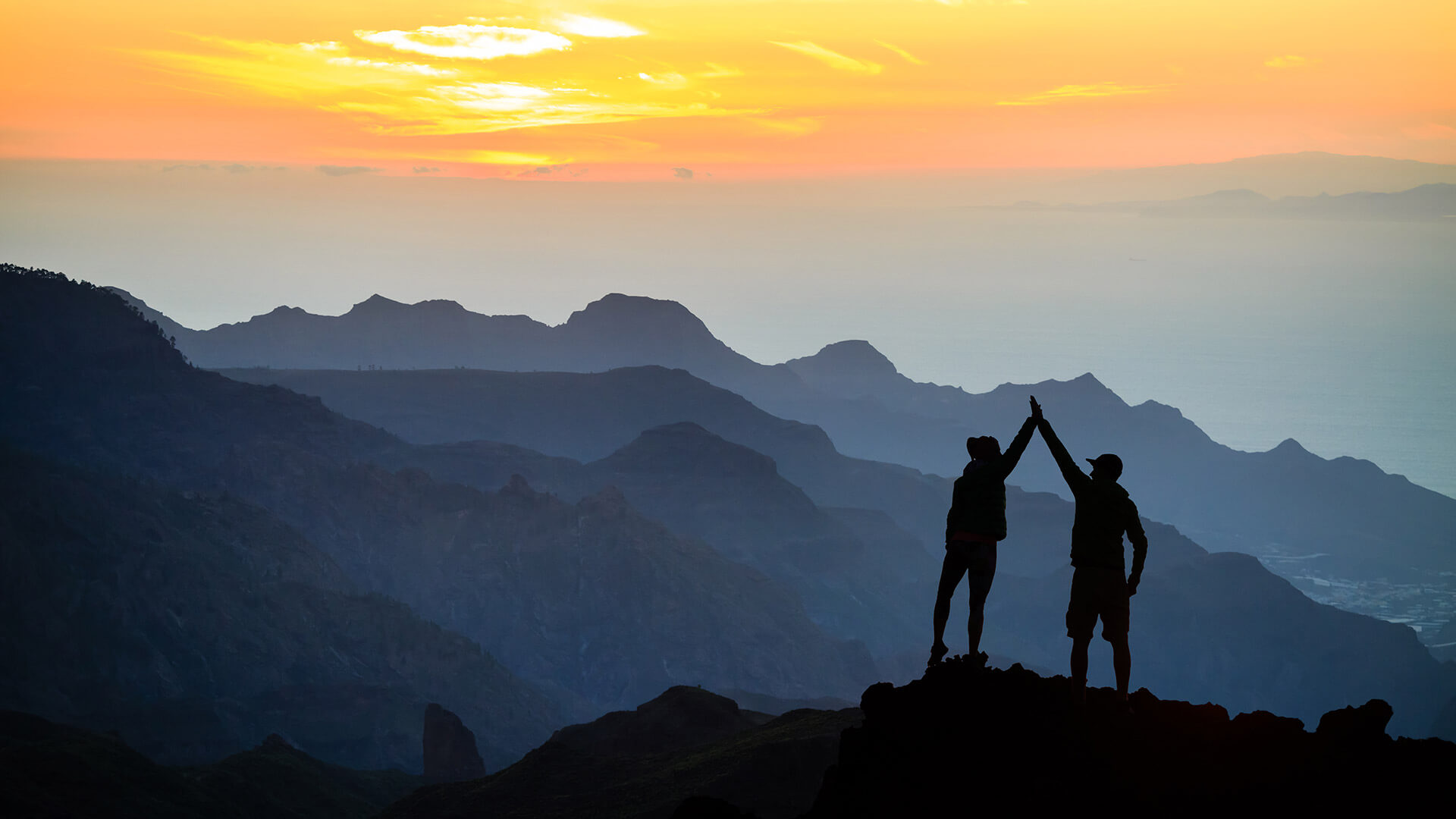 Deux personnes se tapent la main droite pour se féliciter au sommet d'une montagne
