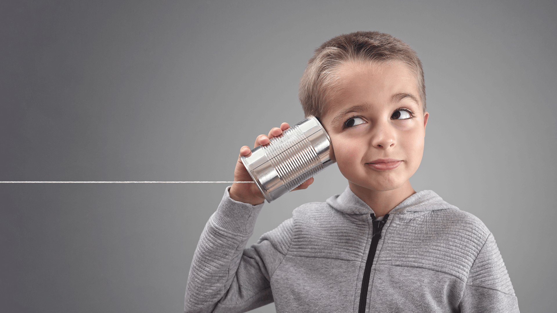 Un enfant écoute dans un téléphone qu'il a fabriqué