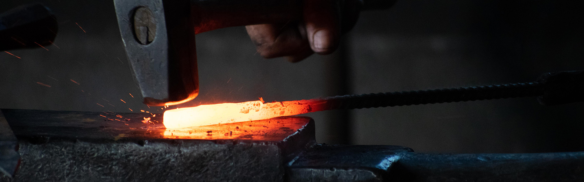 Un marteau frappe un bout de métal incandescent sur une enclume