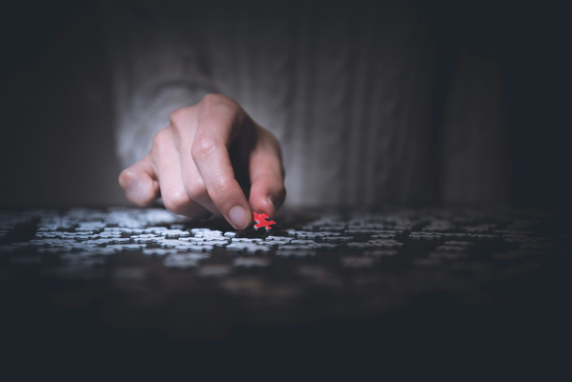 A hand inserts a red puzzle piece.